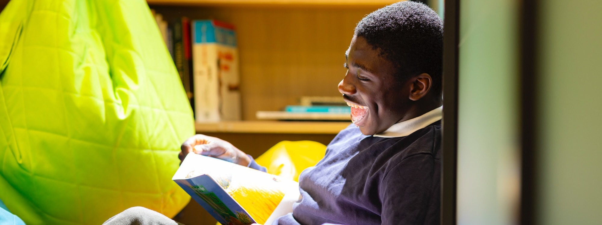 Student sitting reading a book and laughing