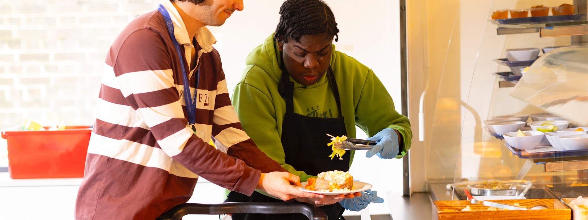 Student and teacher in lunch canteen serving food